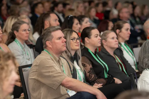 people sitting in chairs looking a stage, some are in focus some are not