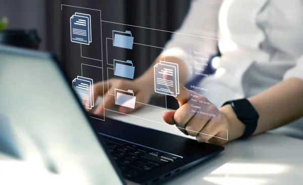 a person in front of a laptop clicking on a floating image of a document