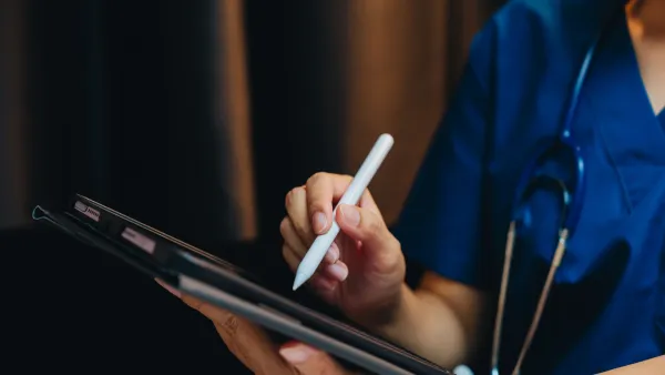 closeup of a doctor in blue scrubs using a tablet