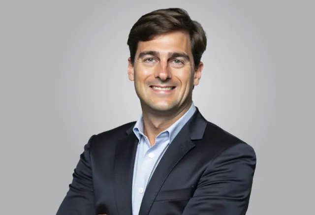 photo of a man in a blue jacket looking at the camera and smiling