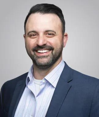 headshot of man smiling wearing a blue coat