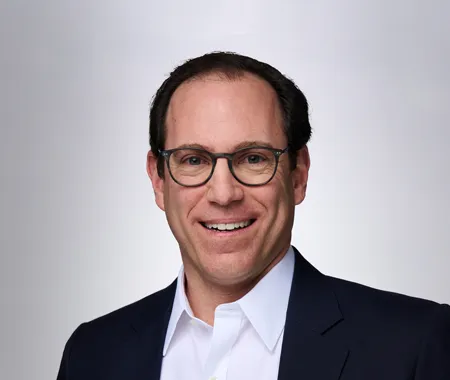 headshot of man with glasses smiling