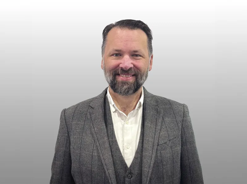 a Man in a gray suite with a beard and dark hair