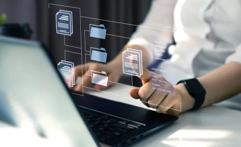 a person in front of a laptop clicking on a floating image of a document