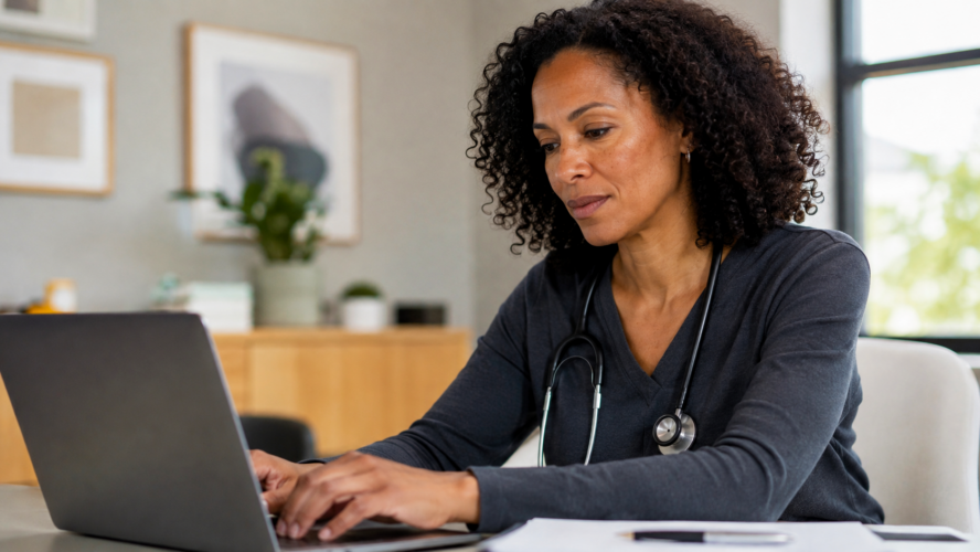 Doctor working at a desk with a laptop, completing clinical documentation